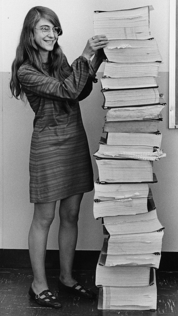 Margaret Hamilton standing with a stack of paper.