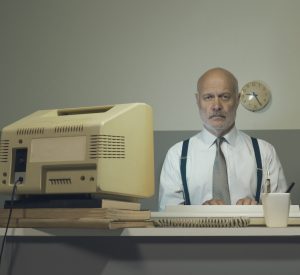 Man sits at desk with old computer.