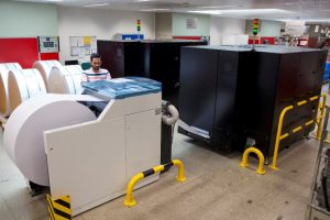 Person operating a continuous feed printer with paper on a roll