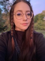 An image of myself, a 27 year old female with long brown hair sporting two small braids and a pair of large frame glasses.