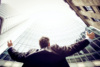 Man arms outstretched toward tall buildings that are surrounding him