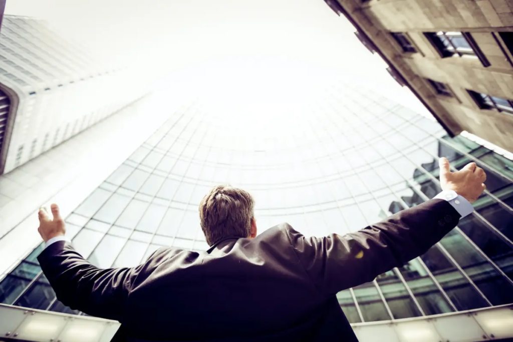 Man arms outstretched toward tall buildings that are surrounding him
