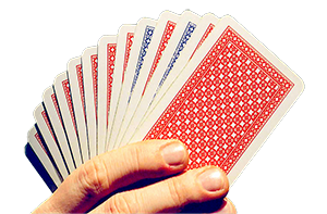 Hand holding playing cards with mostly red cards and a couple of blue cards