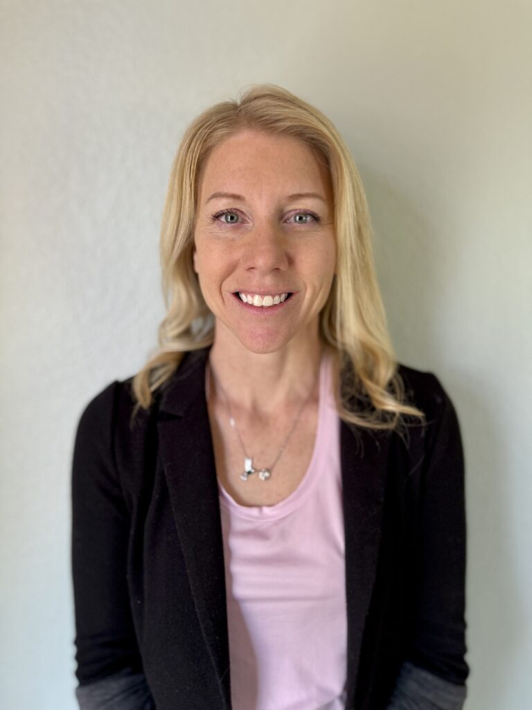 headshot photo of female with blonde hair, pink shirt, and black blazer.