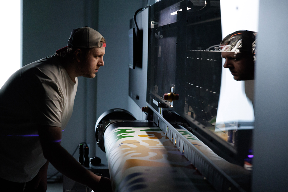 Worker inspecting wallpaper during large-format printing.
